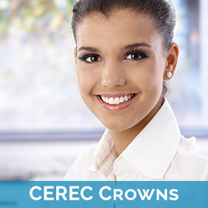 A smiling woman with dark hair, wearing a white blouse and a name tag that reads  CEREC CROWNS , set against a blurred background.