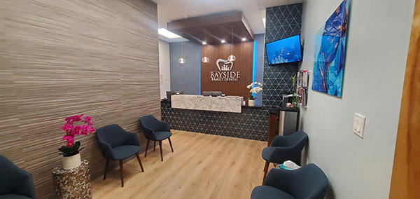 The image shows an interior space, likely a waiting area or reception room, with modern decor and furniture. It features a clean, contemporary design with neutral colors and touches of blue in the patterned wall tiles.