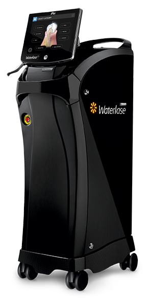 The image shows a medical device, specifically a portable ultrasound machine with a monitor displaying an image of a human body, placed on top of a black cart with wheels, located indoors.