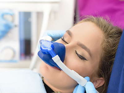 A woman receiving medical oxygen therapy with a clear mask covering her mouth and nose.